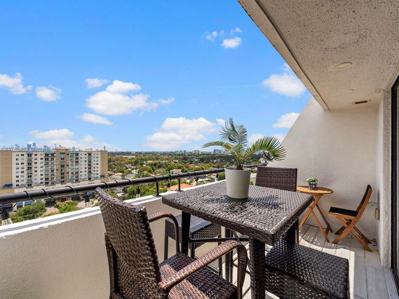 Balcony view with outdoor furniture overlooking cityscape and buildings.