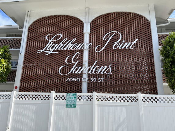Front view of a building named 'Lighthouse Point Gardens' with brick detail.
