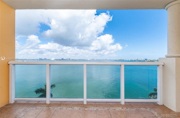 Panoramic view of water and city skyline from a balcony with railing.