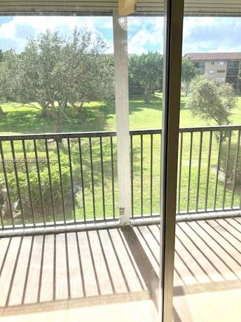 View from a building showing grass and trees in the surroundings.