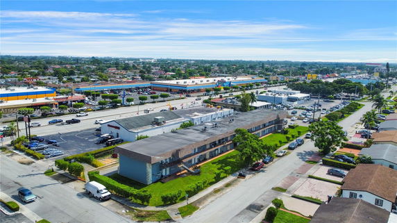 Aerial view of a commercial area with multiple buildings, parking lots, and roads.