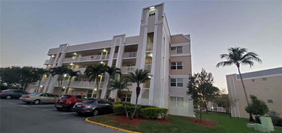 Front view of a multi-story building with balconies and palm trees.