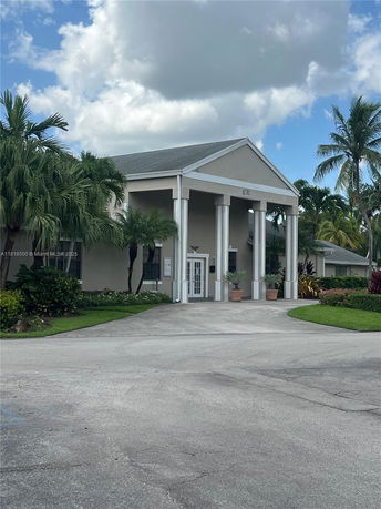 Front view of a building with a gabled roof and columns at the entrance.