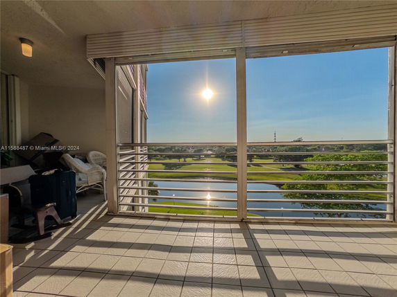 Balcony view overlooking a golf course and water feature at sunset.