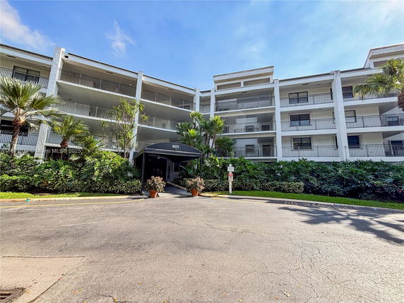 Front view of a multi-story residential building with balconies and an entrance canopy.