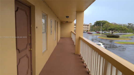 Exterior corridor with view of parking area and neighboring buildings.