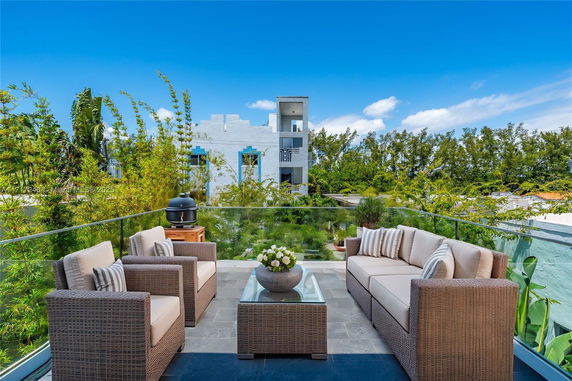 Outdoor seating area on a rooftop with wicker furniture and glass railing.
