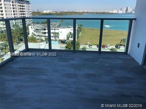 Balcony with a view of buildings and water in the background.
