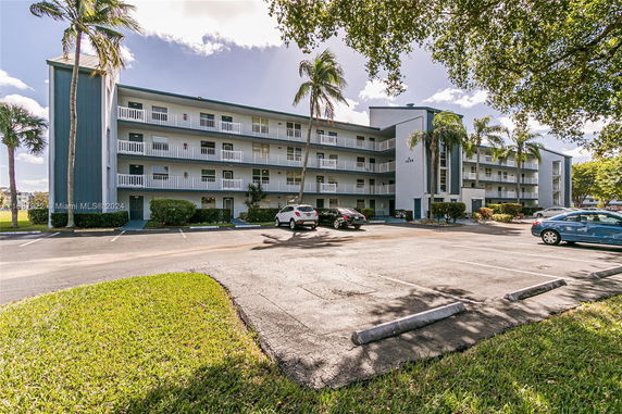Front view of a multi-story building with balconies and palm trees.