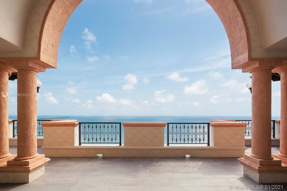 Panoramic view from a balcony overlooking the sea with ornate railings and columns.