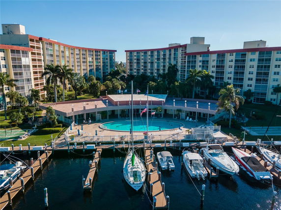 View of a residential complex with a circular swimming pool and adjacent marina.