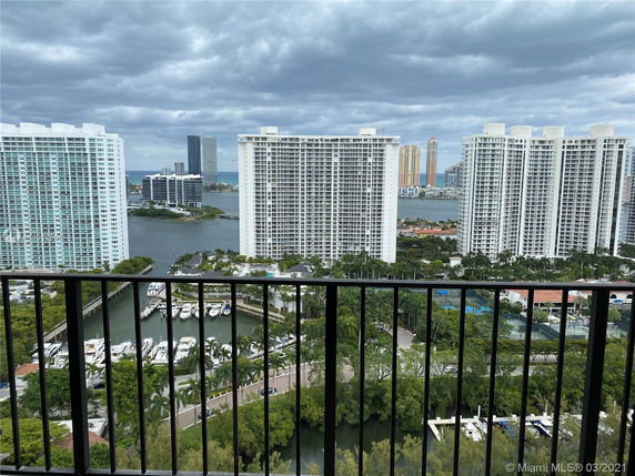 Panoramic view from a high-rise apartment overlooking other tall buildings, a marina, and water bodies.