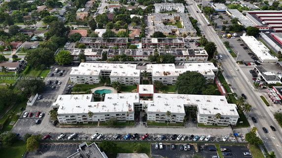 Aerial panoramic view of a residential complex with flat-roofed buildings and a swimming pool.