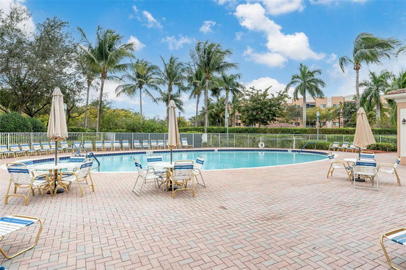 Outdoor swimming pool area with lounge chairs and tables with umbrellas.