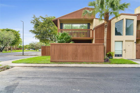 Front view of a two-story house with a wooden fence and balcony.
