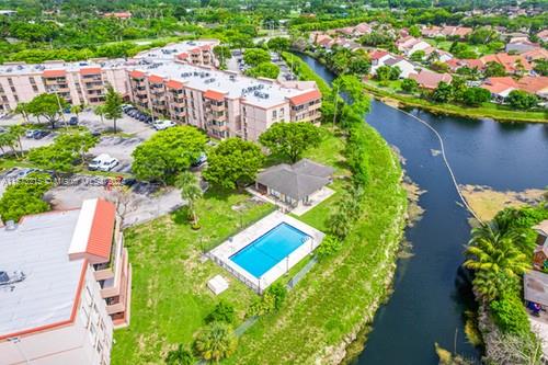 Aerial view of residential buildings with a nearby river and a swimming pool.