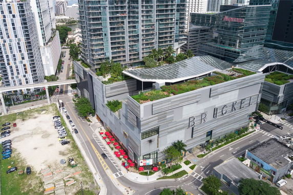 Elevated view of a large modern building with multiple stories and rooftop greenery.