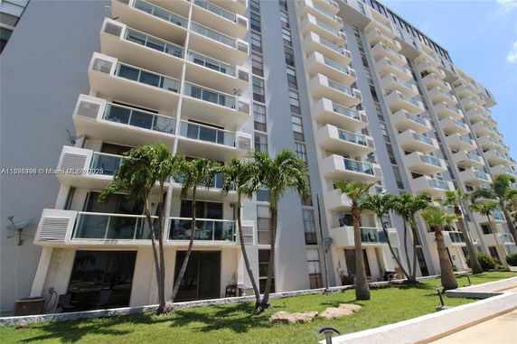 Front view of a high-rise building with balconies and palm trees.