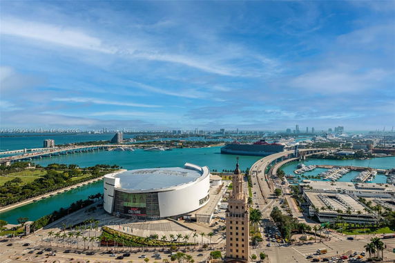Panoramic view of a coastal city with a large arena, cruise ships, and expansive waterways.