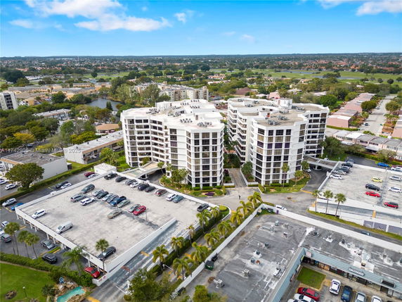 Aerial view of a multi-story apartment complex with surrounding parking areas and greenery.