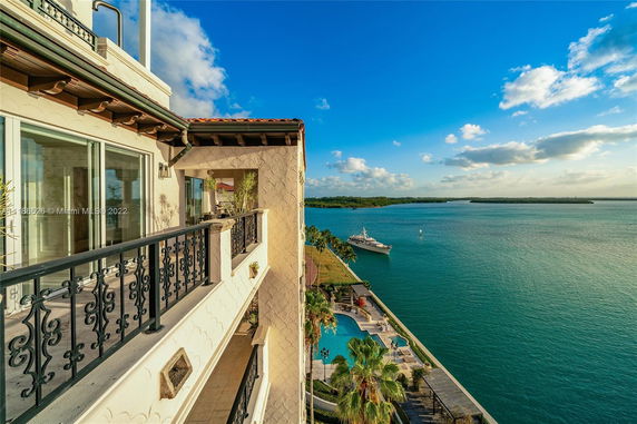 View from a building showing a waterfront with a pool and a docked yacht.