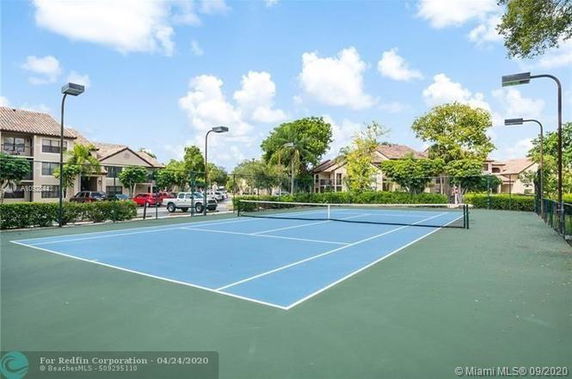 Tennis court located in a residential area with multiple houses visible in the background.