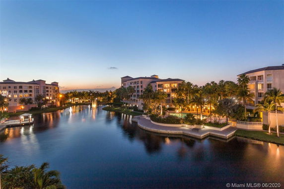 Image of waterfront residential buildings at dusk with surrounding landscape and water features.