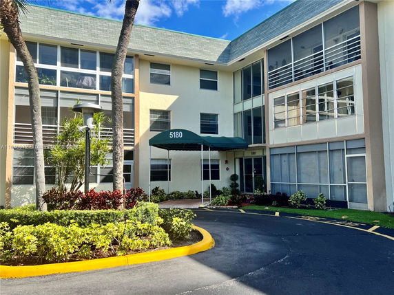 Front view of a multi-story building with large windows and an entrance canopy.