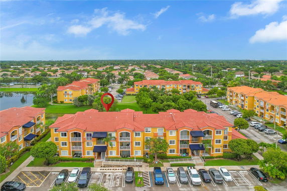Aerial view of residential buildings with red roofs and surrounding greenery.