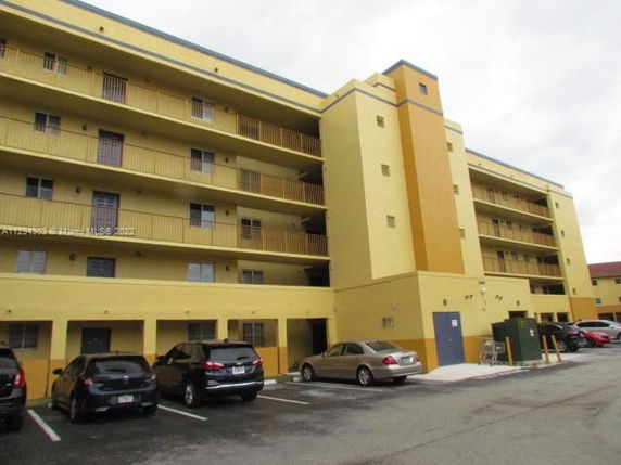 Front view of a multi-story apartment building with parking spaces.