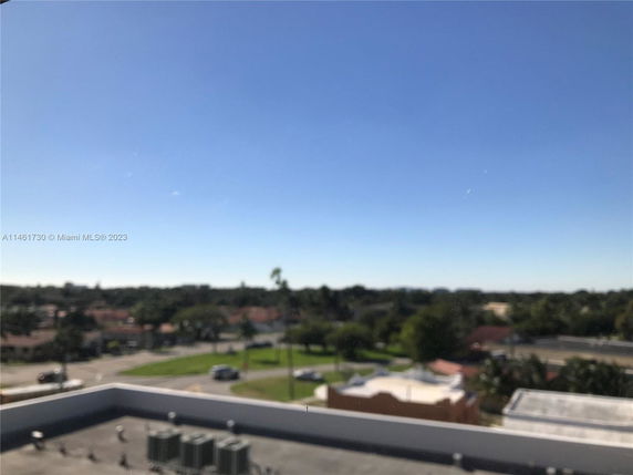 Wide angle view of surroundings from an elevated position, showing buildings and trees in the distance.