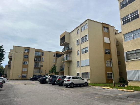 View of apartment buildings with an outdoor parking area.