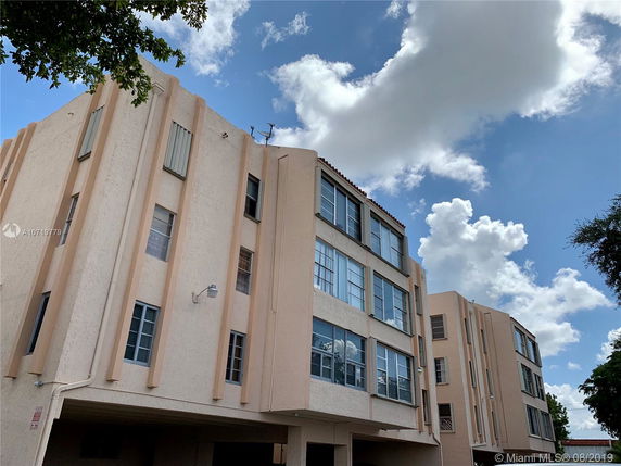 Front view of a multi-story apartment building with beige walls and multiple windows.