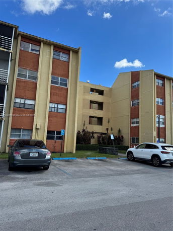 Front view of a multi-story apartment building with a parking area.