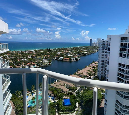 View from a high-rise balcony overlooking a coastal city and ocean.