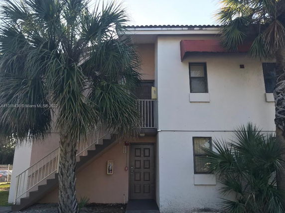 Front view of a two-story building with an exterior staircase and entrance door.