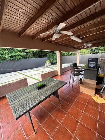 Covered outdoor patio area with ceiling fans and a table.