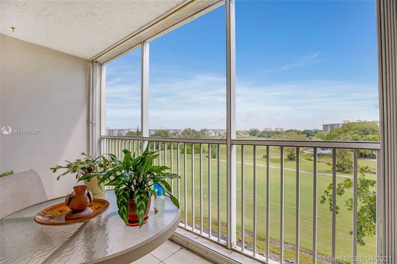 View from a balcony showing a wide expanse of grassy fields and distant buildings.