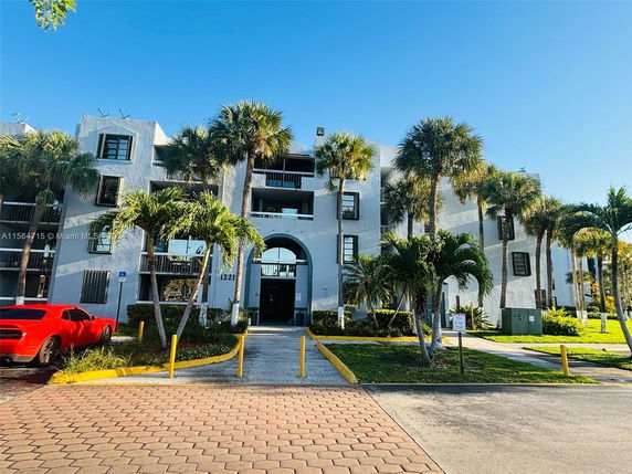 Front view of a multi-story residential building with balconies and palm trees.