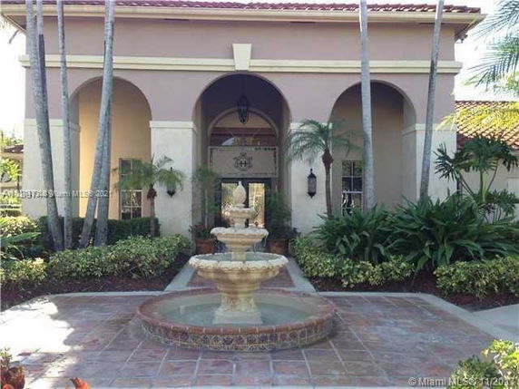Front view of a building with arches and a fountain in the foreground.