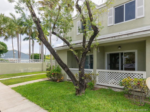 Front view of a two-story house with a small porch and greenery around.