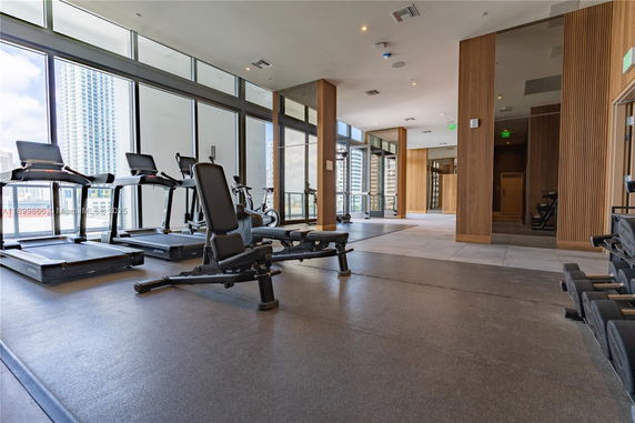 Interior view of a gym area with exercise equipment and large windows.