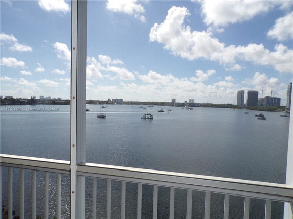 Panoramic view of water body with boats and distant city skyline seen from a balcony.