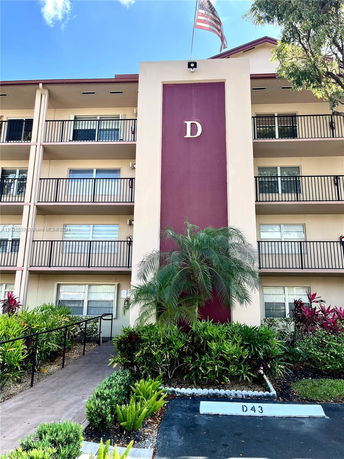 Front view of a multi-story building with balconies and an entrance ramp.