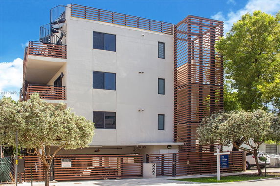 Front view of a modern multi-story apartment building with wooden accents and a spiral staircase on the side.