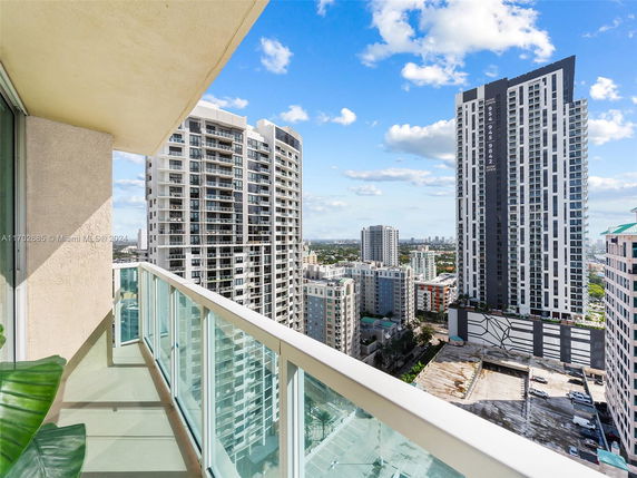 Panoramic view from a high-rise balcony, overlooking surrounding skyscrapers and cityscape.