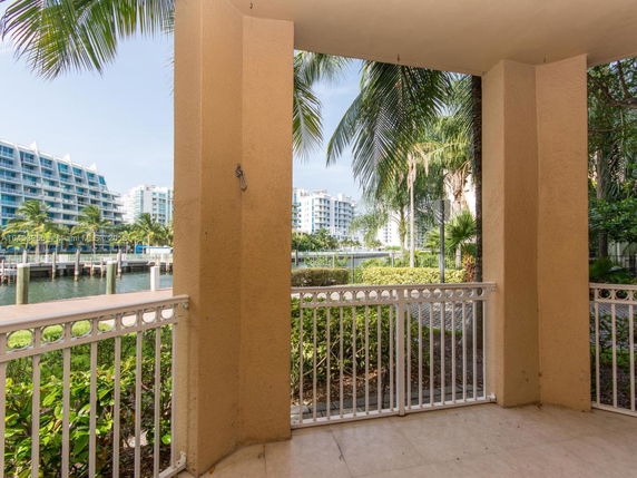 A view from an outdoor covered patio overlooking a waterway and modern residential buildings in the background.