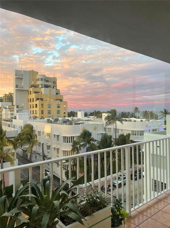 Panoramic view of surrounding buildings and sunset from a balcony.