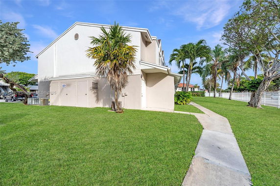 Side view of a multi-story house with palm trees in the yard.