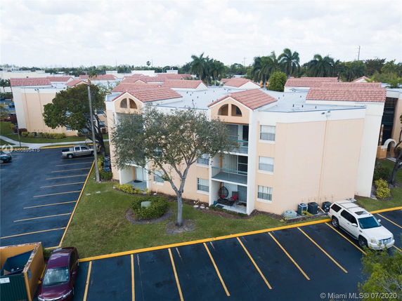 Front view of a multi-story apartment building with parking area.